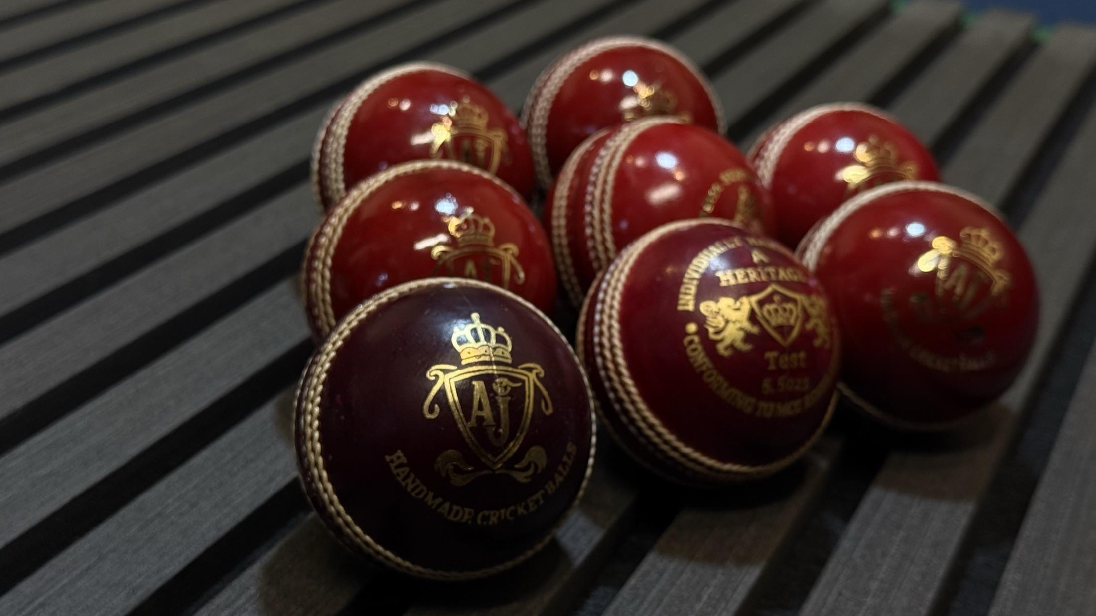 AJ cricket balls on dark wooden slats