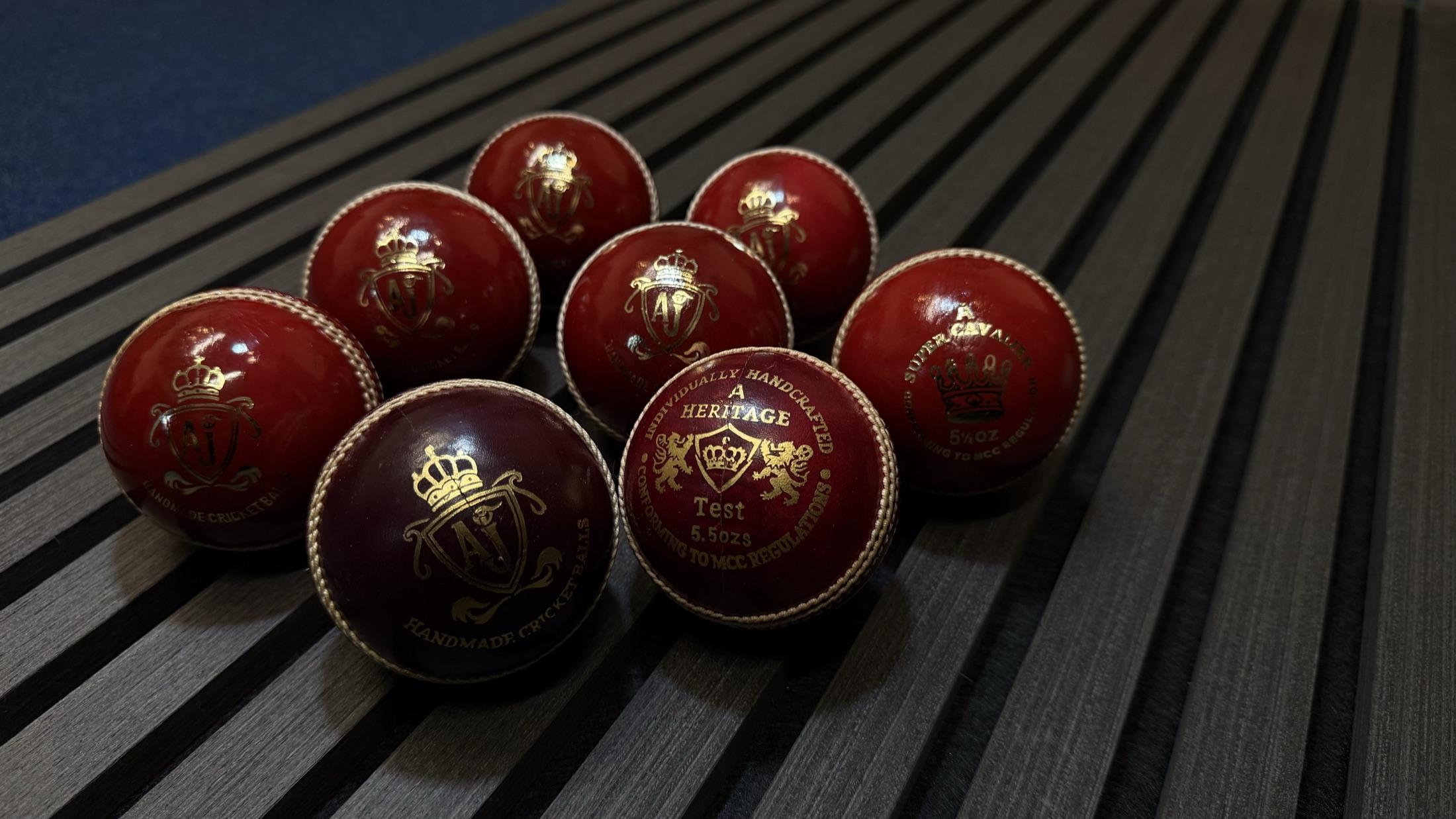 AJ cricket balls arranged on dark wooden slats